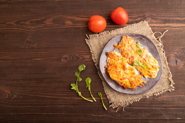 baked chicken meat with cheese and tomatoes on brown wooden. top view, flat lay, copy space