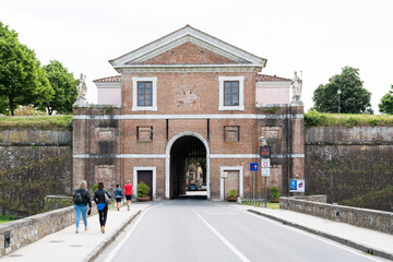 People walking through Porta San Donato, a historic city gate in Lucca, Italy.