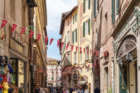 Fototapeta Busy narrow street in Lucca, Italy, with old buildings and walking tourists.