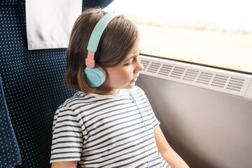 Child with a smartphone and earphones travels by train. Family travelling concept.	