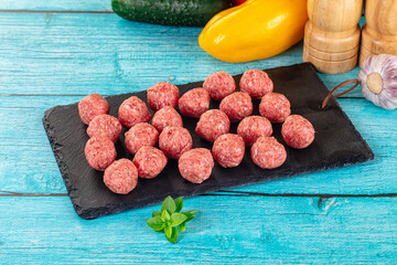 Raw beef meatballs over board