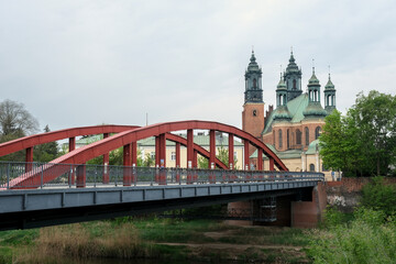 Red bridge leading to the Cathedral of St. Peter and Paul in Poznan, Poland, with green domes...