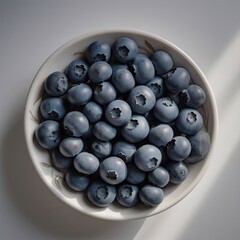 A top down view of fresh blueberries in a white bowl with soft lighting on a white surface top view