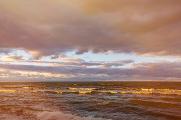 Dark sky over the sea. Low clouds over the water in the bay. Background with a tense panorama of the coast before a storm at sunset.