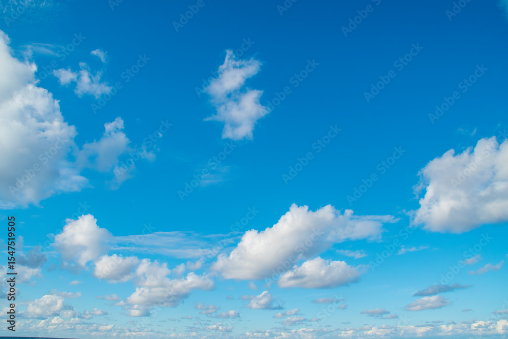 Wall mural a vast expanse of bright blue sky dotted with fluffy white clouds.several clouds of varying sizes ar
