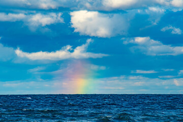 Rainbow over the sea on a cloudy day.