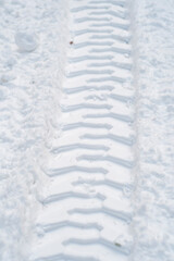 Close-up of tractor tracks on snow-covered cobblestones. Tire tracks on a winter road.