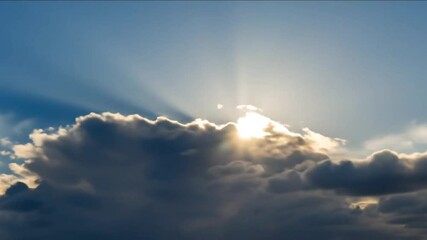 Stunning sunbeam timelapse shining from behind dark clouds in a beautiful blue sky - Powered by Adobe