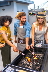 Friends roasting marshmallows at rooftop barbecue party