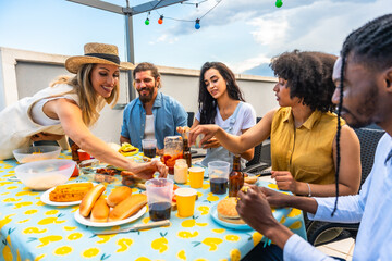 Friends enjoying rooftop barbecue party with hot dogs and burgers