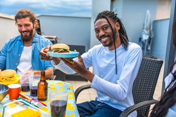 Friends enjoying burgers and drinks at rooftop barbecue party
