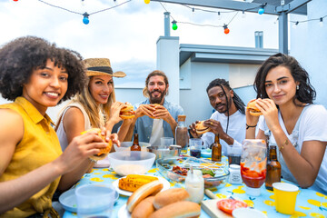 Friends eating burgers at rooftop barbecue party