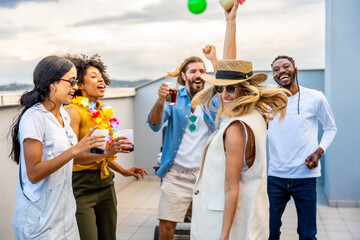 Friends enjoying rooftop party, dancing and drinking cocktails