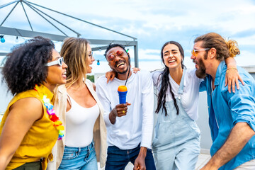 Friends singing karaoke at rooftop party, having fun together