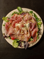 Italian salad with ham, mozzarella cheese, parmigiano cheese, fresh basil, pepper, and salad leaves