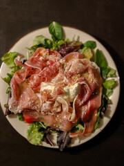 Italian salad with ham, mozzarella cheese, parmigiano cheese, fresh basil, pepper, and salad leaves