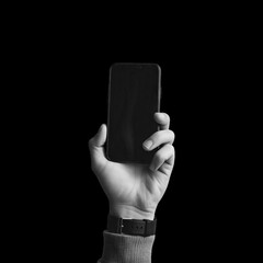 Hand holding a black smartphone with a black watch on the wrist against a black background