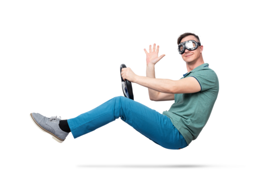 Man in goggles pretending to drive an invisible car, floating mid-air with steering wheel and waving hand. Concept of imagination, humor, levitation. Isolated on transparent background PNG.