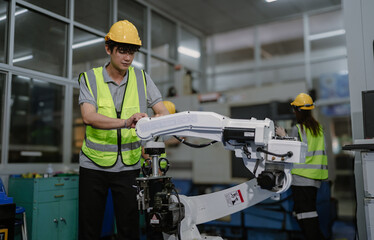 Robot maintenance engineer working on robot arm connection. Young adult man learning training robotic machine engineering in futuristic electronic education academy. Artificial intelligence technician