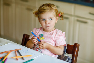 Cute adorable baby girl learning painting with pencils. Little toddler child drawing at home, using...