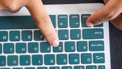 Finger pressing control and D or ctrl + D shortcut keys on a green wireless computer keyboard...