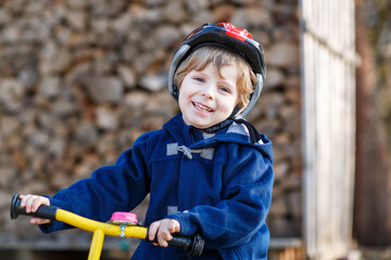 Little boy riding bicycle in village or city. Happy preschool child on balance bike, having fun. Outdoor leisure and games for children.