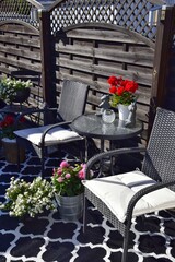 Two wicker chairs with a table, flowers in pots. A place to rest and relax.