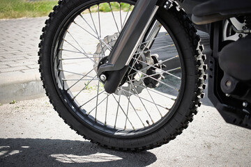 Fototapeta premium Close-up of a motorcycle front wheel on a sunny day in a parking area