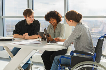Teamwork brainstorm. Diverse multiracial colleagues woman in chair for people with disability working together. Group of people sitting in creative office discussing business. Young professional team