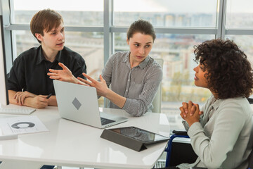 Teamwork brainstorm. Diverse multiracial colleagues woman in chair for people with disability working together. Group of people sitting in creative office discussing business. Young professional team