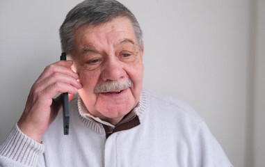 Fototapeta premium A phone call, laughter, and an elderly man in a house, living room, and a conversation with a contact and happy person. A house, communication, and an elderly man with a smile inviting, spending time 