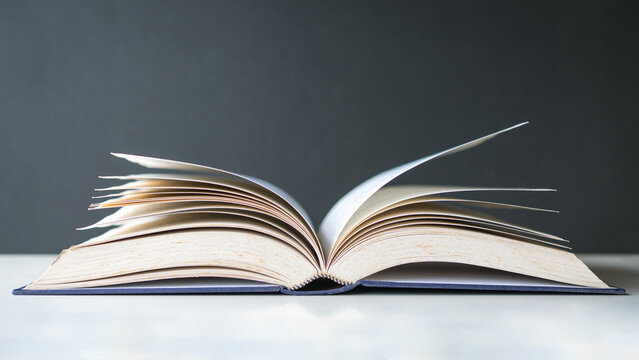 Open book with pages turning. Isolated on dark background. Education or academic concept.