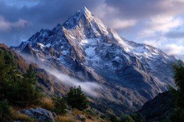 Obraz premium Snow-capped mountain peaks rise dramatically under a cloudy sky during early morning light