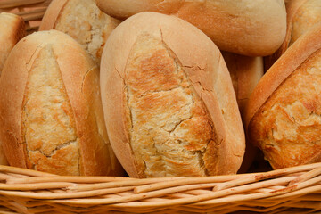 A close-up view showcases a woven basket filled with freshly baked, golden-brown bread rolls, highlighting their rustic texture and inviting appearance