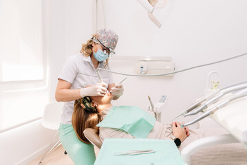 Female Dentist using dental tools while examining patient's teeth in dental clinic