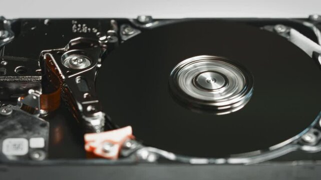 Close-up of an open hard disk drive HDD with spinning platters and visible actuator arm. The image focuses on the inner mechanical components of the storage device