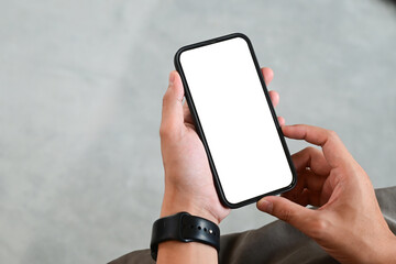 A person is holding a cell phone with a black band on their wrist. The phone is turned off and the screen is blank