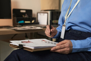Middle aged Caucasian woman sitting at desk analyzing fingerprint records and mugshot photographs...