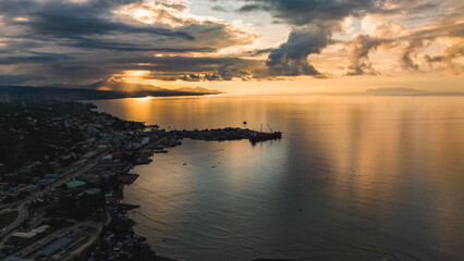Aerial view of a beautiful golden tropical sunset reflected on the ocean.