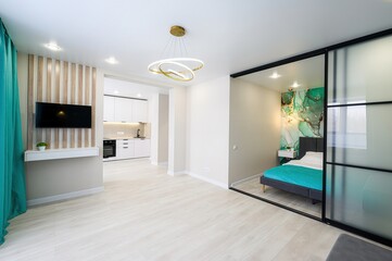 Modern apartment featuring a stylish living area, sleek kitchen, and a bedroom separated by glass...