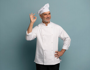 Portrait of a smiling male chef cook showing ok sign isolated on blue background.