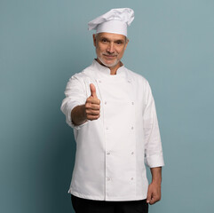 cooking, culinary and people concept - happy smiling mature male chef showing thumbs up over blue