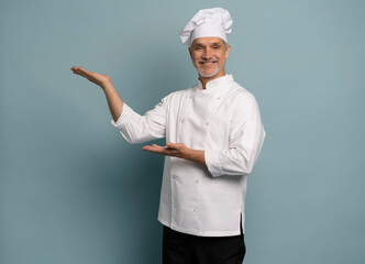 Mature male chef presenting something over blue background.