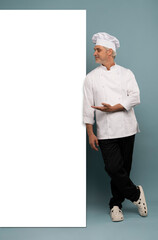 Mature male chef presenting something over blue background.