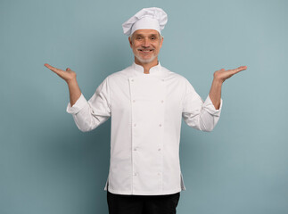 Mature male chef presenting something over blue background.