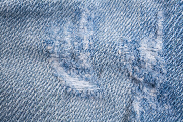 Closeup detail of torn on blue jeans. Denim jeans texture.