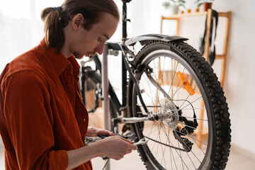 Young man choosing wrench for bicycle repair and maintenance at home