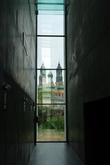 Historic church towers in Poznań framed by a modern glass corridor, merging contemporary...