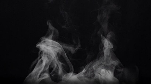 White natural rising steam from food or hot drink isolated on a black background.