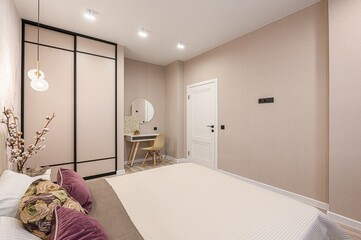 cozy bedroom featuring a large bed, floral wallpaper, and a modern vanity area with a round mirror...